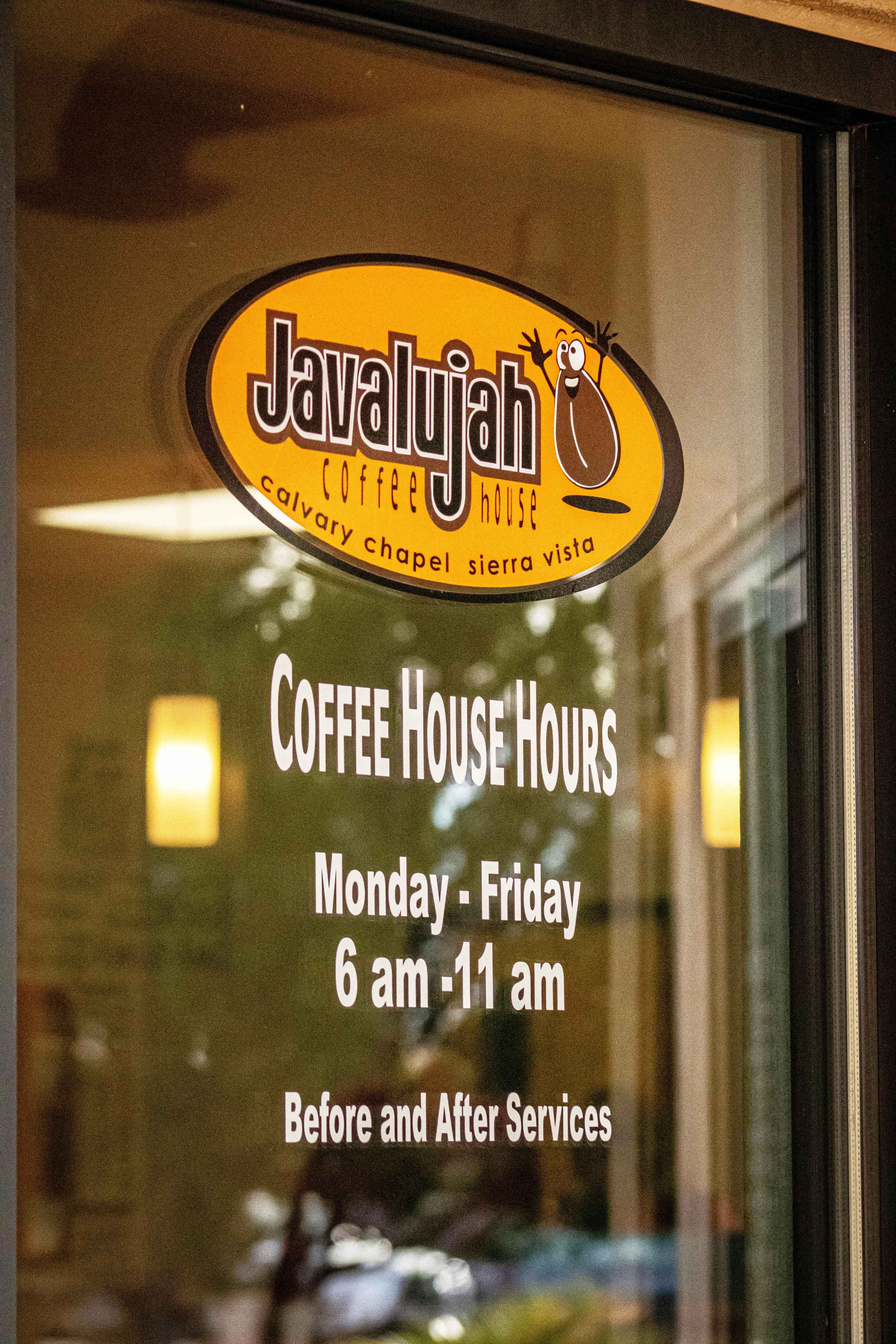A glass door with the "Javalujah Coffee House" logo and hours of operation: Monday to Friday 6 am to 11 am, and before and after services.